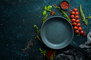 Wall Mural - Culinary banner. Frying pan with vegetables on a black stone background. Top view. Rustic style.