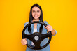 © deagreez - Portrait of her she nice-looking attractive lovely pretty charming cheerful brunet girl turning steering wheel isolated on bright vivid shine vibrant yellow color background