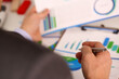 © H_Ko - Close up of businessman with pen in hand analyzing reports, financial charts and graphs at work