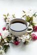 cup of healthy black tea in front of a white background surrounded by colorful flowers