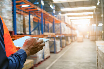 The  man holding tablet to checking the stock products,Employee using warehouse software to checking the stock of products in the warehouse,spot focus hand hold tablet.