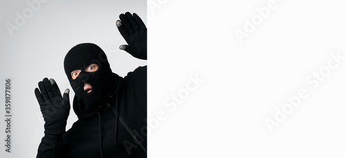 Cuadros en Lienzo Masked thief with raised arms isolated on white wall