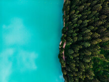 Aerial Top View Of Magically Beautiful Color Water Meets The Shore With A Beautiful Fir-tree Coniferous Forest. Bird's Eye View Of Turquoise Reservoir Basin, Unique Place In Natural Protected Park