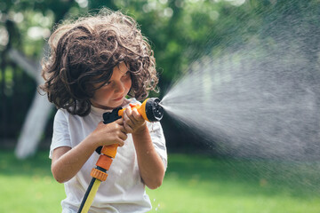 fun child plays with water in the backyard in the garden
