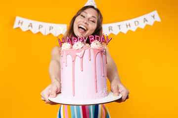 Wall Mural - Image of excited young woman showing birthday torte and smiling