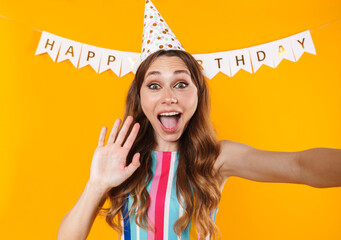 Wall Mural - Image of joyful cute woman taking selfie photo and waving hand