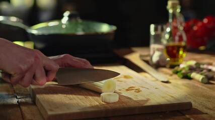 Wall Mural - Woman slicing leek and vegetables for cooking on kitchen table. Closeup hands. Cosy dark room.