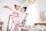 Fototapeta Tulipany - Young attractive mother and her little daughter having fun at pajamas party. Family in the morning