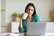 © Prostock-studio - Office Girl At Laptop Having Coffee Sitting At Workplace Indoors