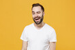 © ViDi Studio - Cheerful funny young bearded man guy 20s in white casual t-shirt posing isolated on yellow wall background studio portrait. People sincere emotions lifestyle concept. Mock up copy space. Blinking.