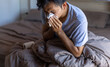 © anut21ng Stock - Young man with a cold blowing her runny nose with tissue. Asian man get sick sneezing from flu. Healthcare and medical concept.