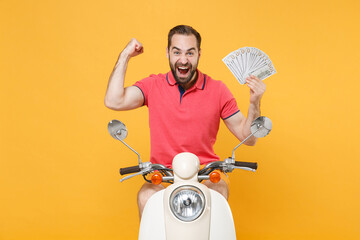 Wall Mural - Happy young bearded man guy in summer clothes driving moped isolated on yellow background. Driving motorbike transportation concept. Hold fan of cash money in dollar banknotes, doing winner gesture.