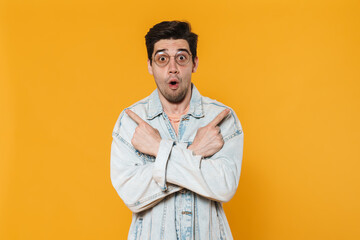 Poster - Photo of surprised young man in eyeglasses pointing fingers aside