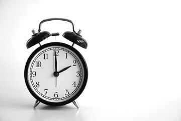 Black vintage alarm clock on table. White background. An image of a retro clock showing 02:00 pm/am.