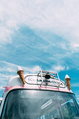 Wall Mural - Ice cream cone with a pink retro ice cream truck or van in the background. High quality photo. Summer vibes in pastel colours. 