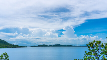 Tropical island background with fluffy cloud in the blue sky and trees in the foreground