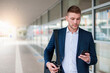 © Westend61 - Portrait of a young businessman in the city checking his smartphone