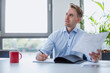 © Westend61 - Businessman sitting at table in conference room holding papers