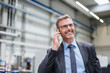 © Westend61 - Smiling businessman on the phone in a factory
