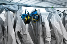 Protective Suits And Masks Hanging From Rack In Locker Room