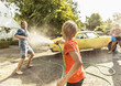 © Westend61 - Friends washing yellow vintage car in summer having fun
