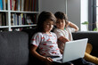 © Westend61 - Siblings sitting with laptop on sofa in living room at home