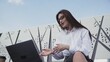 Young caucasian business woman with long hair talk on skype using laptop sitting outdoor.