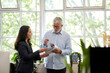 © Bec Hannaford/Austockphoto - Professional business woman and man standing, discussing paperwork