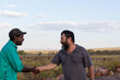 © Caro Telfer/Austockphoto - Two men shaking hands in the outback