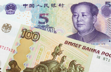 A macro image of a Russian one hundred ruble note paired up with a purple, blue and white five yuan bank note from China.  Shot close up in macro.