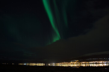 aurora borealis, northern lights over mountain landscape with new snow reflecting on beach sand and 