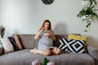 © Boris Jovanovic/Stocksy - Pregnant woman eating watermelon on a cozy couch
