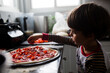 © Maria Manco/Stocksy - Boy makes home made pizza at home in the kitchen
