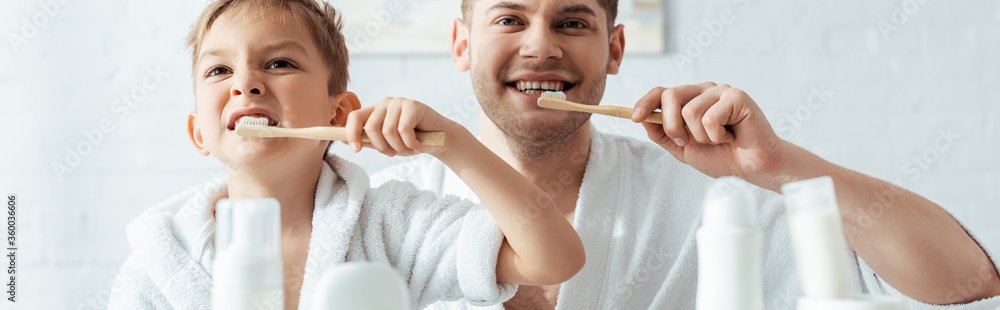 selective focus of happy father and son brushing teeth together, panoramic shot - obrazy, fototapety, plakaty 