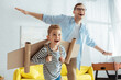 happy boy with carton plane wings, and cheerful father having fun while imitating flying
