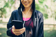© chika_milan - Closeup of smiling caucasian female runner standing in nature and using smart phone.