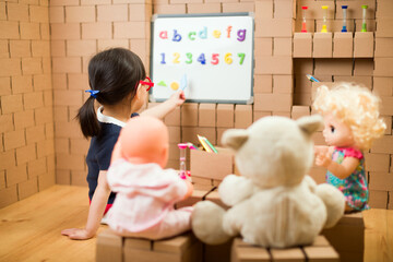 Wall Mural - toddler girl pretend play as a teacher at home