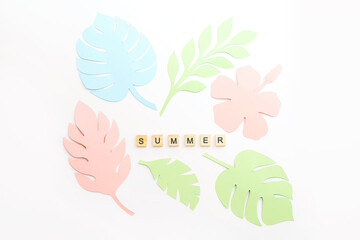 Summer word written on wooden blocks and tropical leaves on white background. Paper cut style. Exotic summertime. Top view