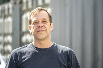 street portrait of a man 40-50 years old in a black t-shirt on a neutral blurred background. perhaps