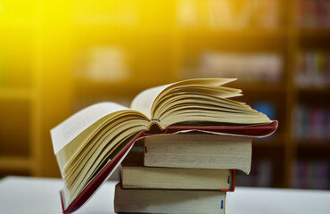 Open Book on wood table and blurred bookshelf in the library, education background, back to school concept.