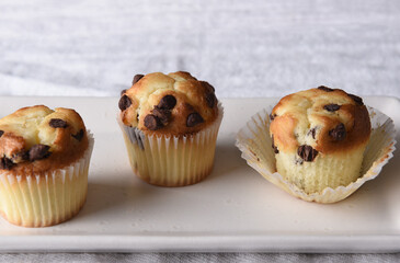 Wall Mural - Closeup of three mini chocolate chip muffins on a white serving plate