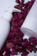  two white shampoo bottles and no label near a pile of little pink roses. body care and beauty concept. Copy space. High quality photo