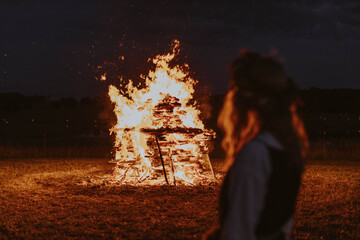 Wall Mural - Woman watching midsummer holidays night fire in Latvia