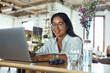© puhhha - Freelancer. Business Woman Working On Laptop Remotely At Cafe. Fashion Girl In Glasses Sitting In Restaurant And Typing Something. Smiling Female Looking At Camera Portrait.