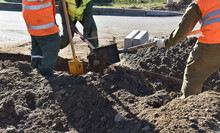 Workers Throw Earth With Construction Shovels, Dig A Hole For Road Curbs.