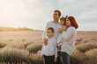 © Med Photo Studio - Laterla view of a young happy family: father, mother,  son and daughter are posing in the middle of the lavender field.