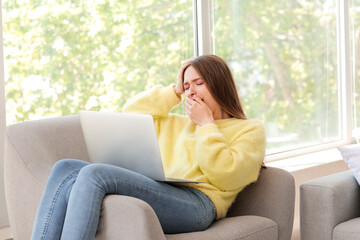 Canvas Print - Young woman suffering from sleep deprivation with laptop at home