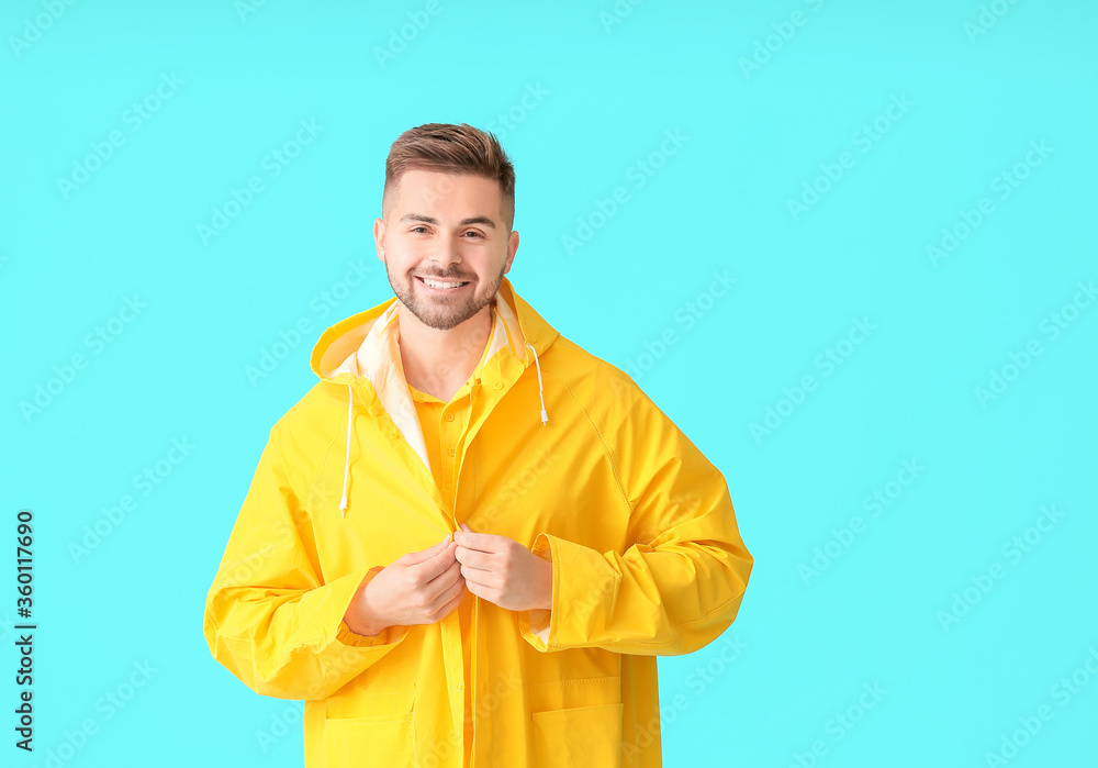 Young man in raincoat on color background