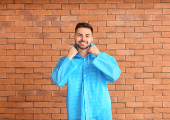 Wall Mural - Young man in raincoat on brick background