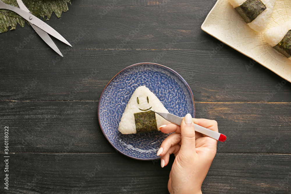 Woman preparing traditional Japanese onigiri on table